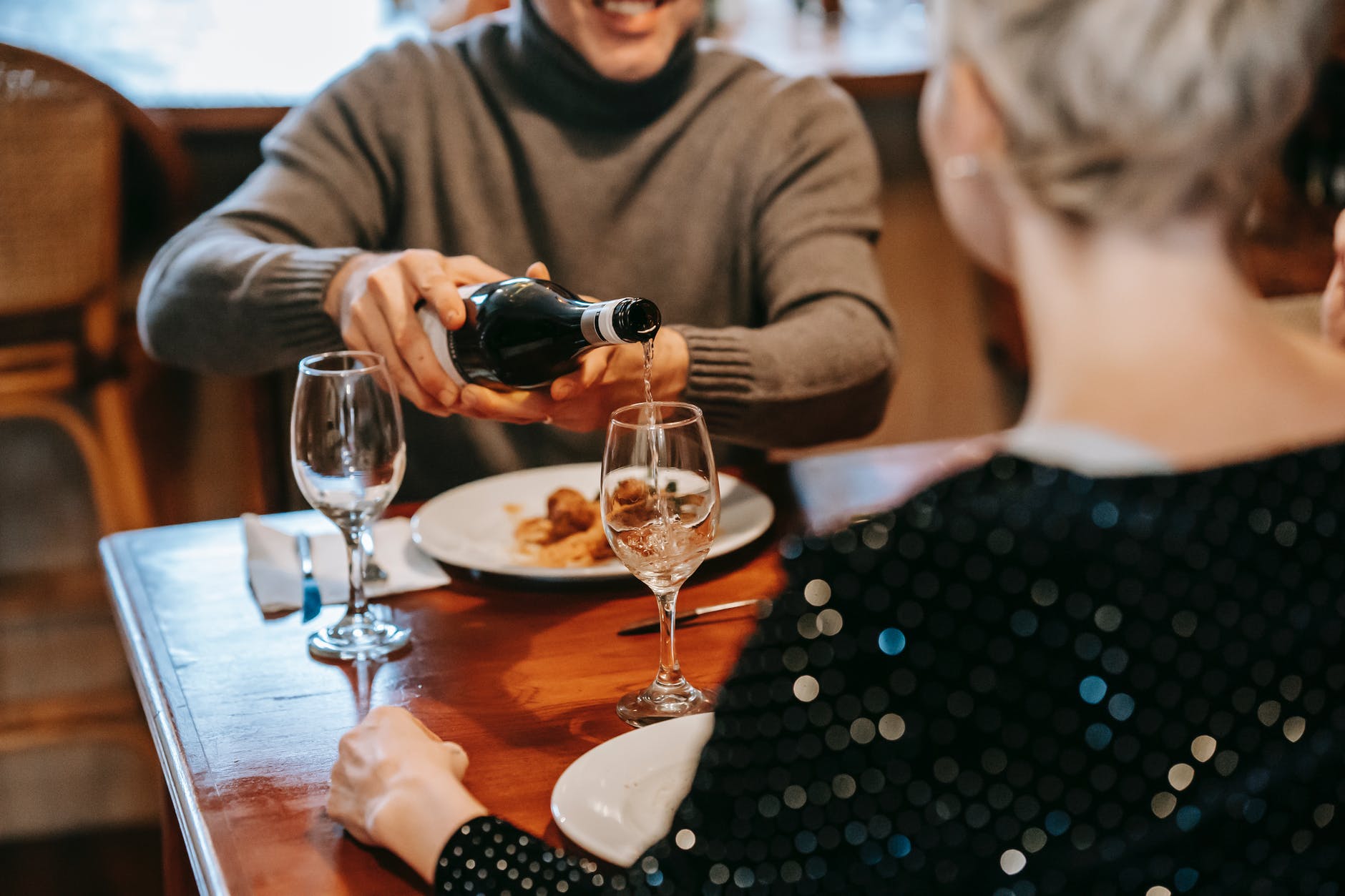 anonymous couple having date with wine and food in restaurant