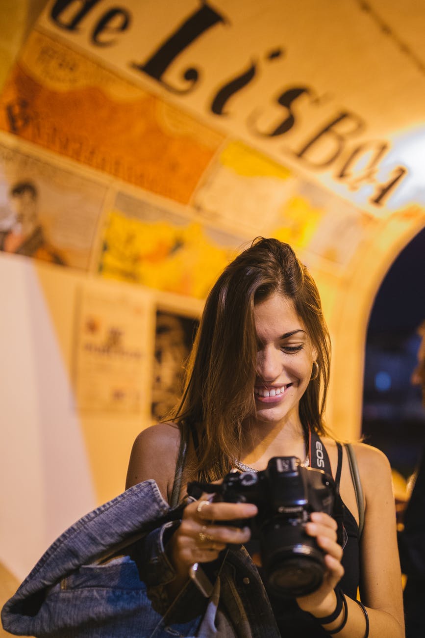 selective focus photography of woman smiling holding dslr camera