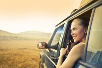 cheerful woman in car enjoying sunset