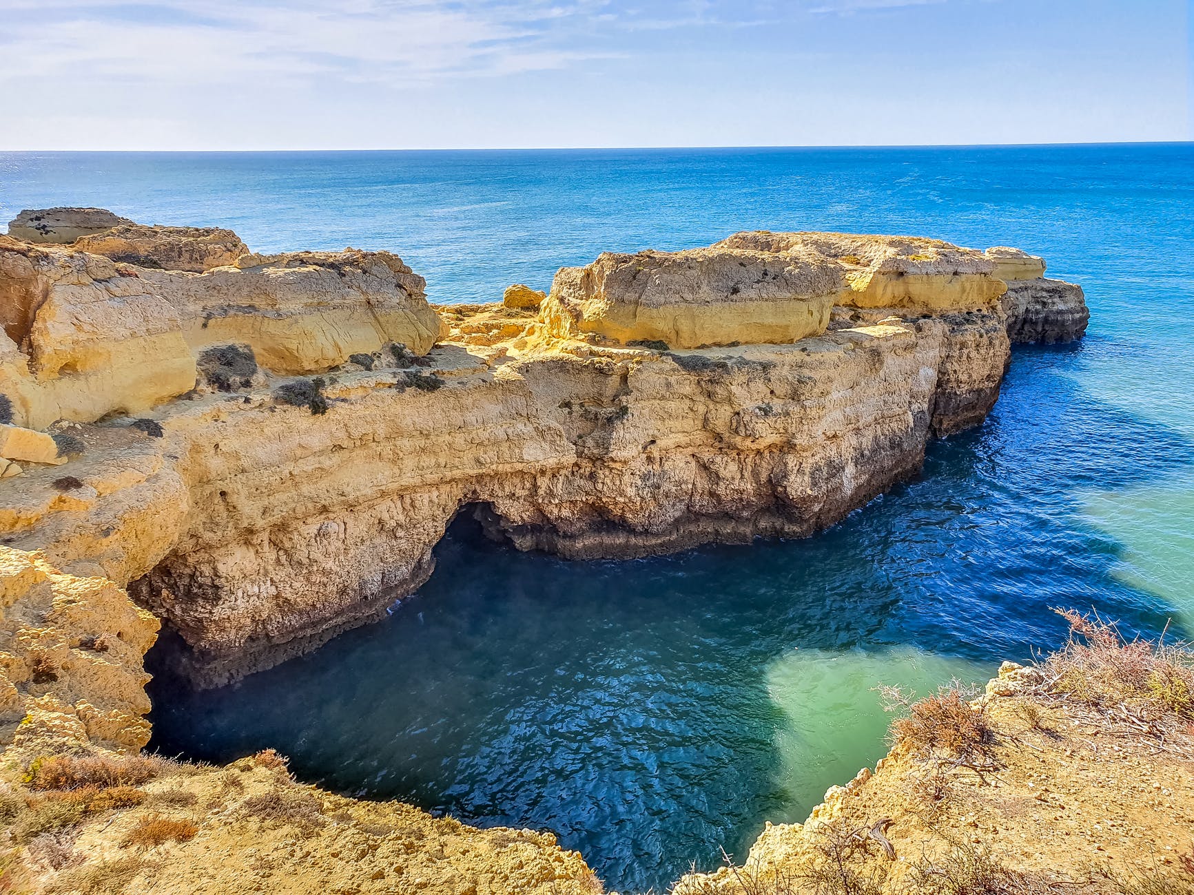 brown rock formation on blue sea under blue sky